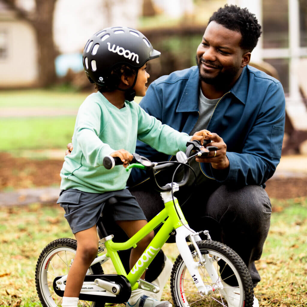 Child on lime woom bike with parent